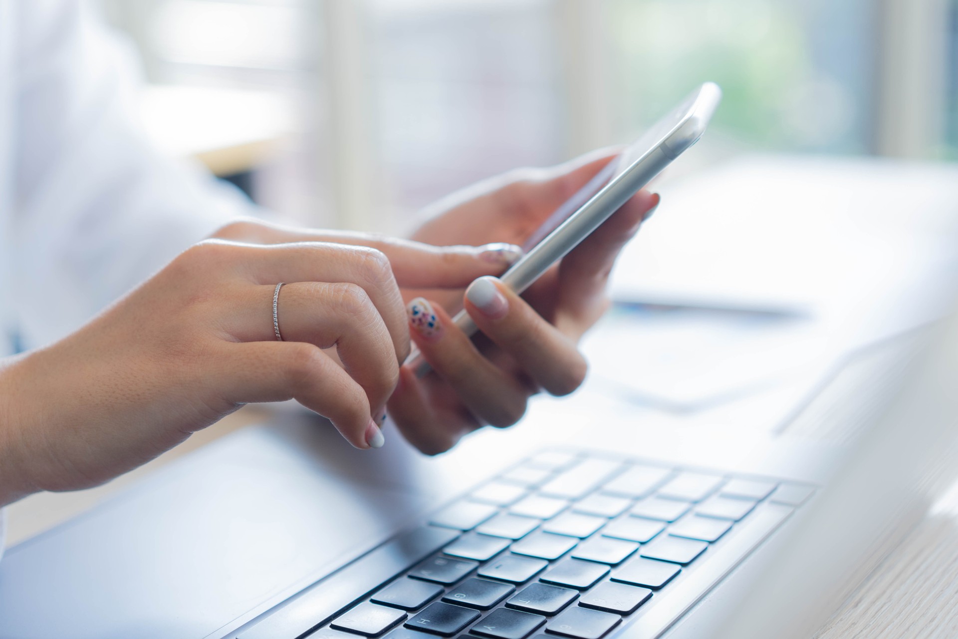 Ausnähen Sie junge Frau, die das Smartphone hält, um Social Media zu spielen oder zu arbeiten oder kontaktiere mit Partner und Kunden am Bürotisch für Business- und Servicekonzept